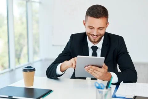 Happy successful businessman in elegant suite using tablet sitting in modern Stock Photos