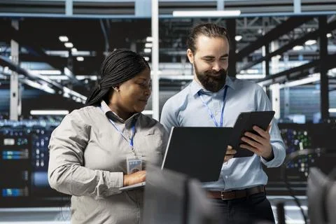 Happy system administrators in data center using devices, verifying firewall Stock Photos