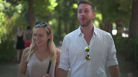 Happy talking couple walking under trees Stock Footage 77911756