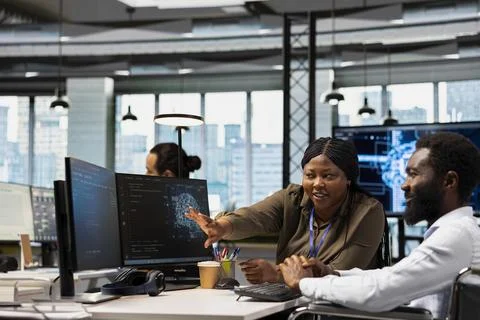 Happy team leader oversees developer in wheelchair using AI automation Foto stock