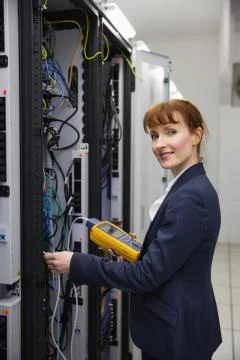 Happy technician using digital cable analyzer on server Stock Photos