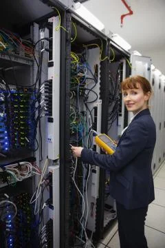 Happy technician using digital cable analyzer on server Stock Photos
