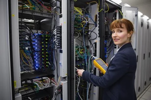 Happy technician using digital cable analyzer on server Stock Photos