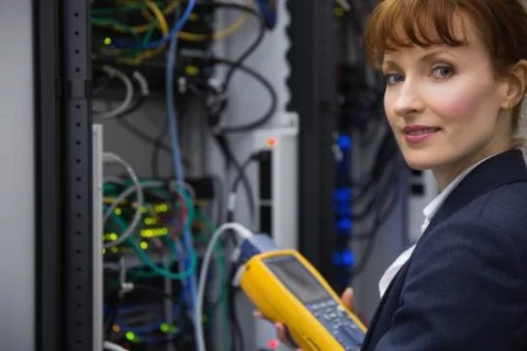 Happy technician using digital cable analyzer on server Stock Photos