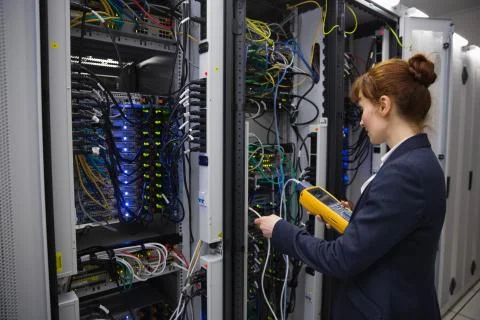 Happy technician using digital cable analyzer on server Stock Photos