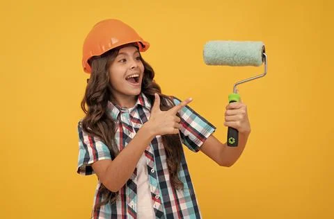 Happy teen girl with curly hair in construction helmet pointing finger on paint Stock Photos