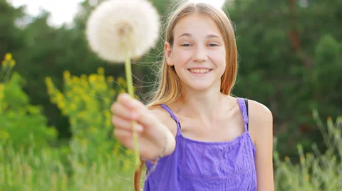 Happy teenage girl holding out hand with dandelion at camera. Health and allergy Stock Footage 30112182