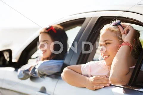 Happy teenage girls or women in car at seaside Stock Photos