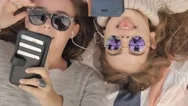 Happy Teenage Girls With Sunglasses Texting Social Media Listening To Music Stock Footage