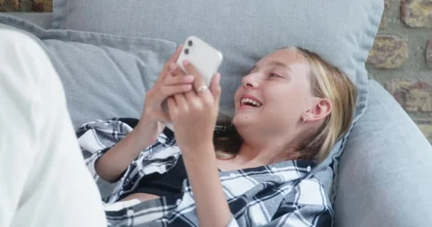Happy teenager using smartphone while relaxing on sofa during breaktime Stock Footage 271320253
