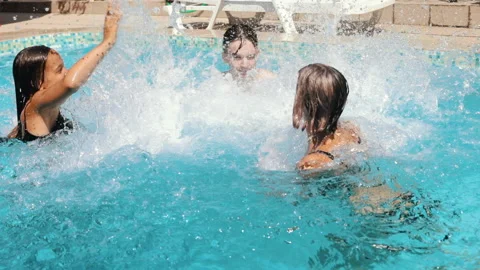 Happy teens having fun in a pool splashing water slowmo Stock Footage 179480449