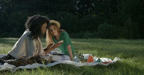 Happy time-spending of two multi race girlfriends on a picnic. The beautiful Stock Footage 84641010