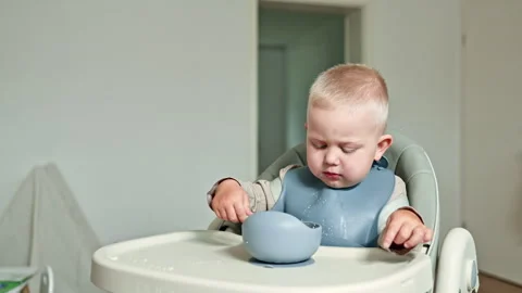 Happy toddler eats with a spoon by himself, child eats milk porridge. Boy 2 Stock Footage 319919977