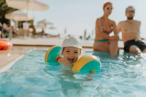 Happy toddler playing in pool during summer vacation. Stock Photos