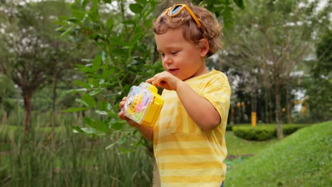 Happy toddler pressing the button to turn on bubble generator toy camera Stock Footage 277107352