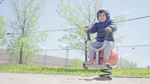 Happy toddler swinging in the park. Cute boy having fun in spring playground Stock Footage 242192653