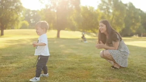 Happy toddler takes first steps as mom walks beside and claps in support. Stock Footage 310439009
