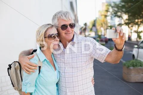 Happy tourist couple taking a selfie in the city Stock Photos