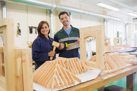 Happy trainee and instructor standing behind construction Stock Photos