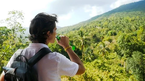 Happy traveler man with backpack drinking beer in mountains. slow motion Stock Footage 100970887