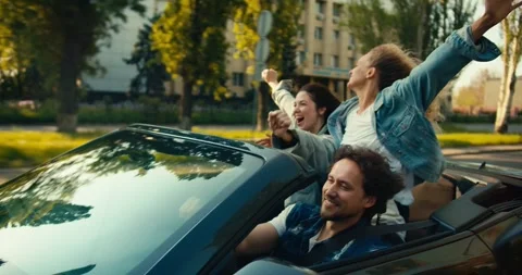 A happy trio: a guy and two girls are riding in a gray convertible. A blonde Stock Footage 245986173