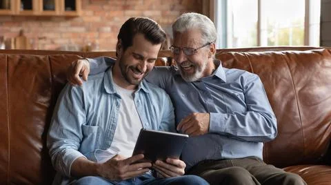 Happy two generations of men having fun with tablet together Stock Photos