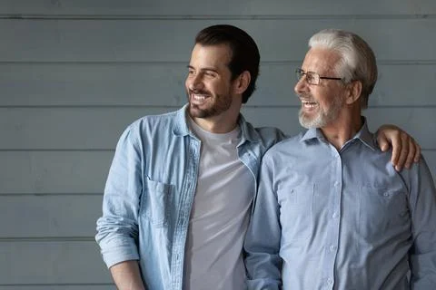 Happy two generations of men hugging, looking in distance Stock Photos