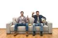 The happy two guys with a beer watch a football on the sofa Photo