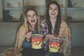 The happy two women with a popcorn watch a movie on the sofa Photo