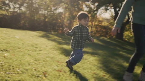 A happy two-year-old kid happily runs to his mother. On a green meadow in the Stock Footage 165982535