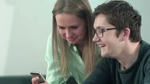 Happy two young students sitting at table and reading text message in libraly in 스톡 동영상 90150957
