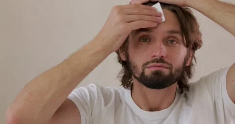 Happy unshaved man using cleansing lotion for facial skin. Young guy doing Stock Footage 142528406