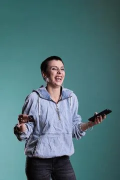 Happy woaman smiling while doing online shopping holding phone while typing Stock Photos