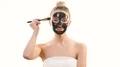 The happy woman applying a skin care face mask on the white background 4k or 4k+ Resolution