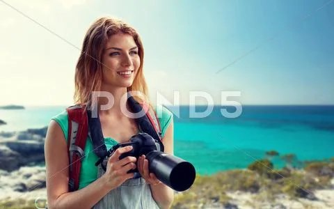 Happy woman with backpack and camera over seashore Stock Photos
