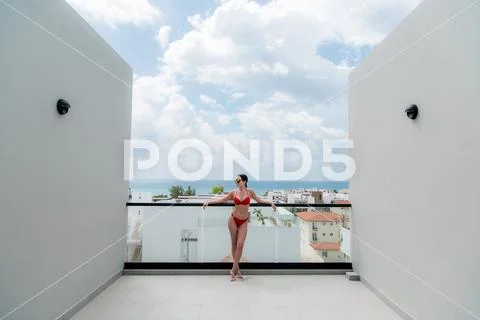 Happy woman beside a rooftop pool with a beautiful city and ocean view on Stock Photos