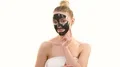 The happy woman with a black face care mask flirts on the white background 4k or 4k+ Resolution