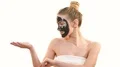 The happy woman with a black face care mask gesturing on the white background 4k or 4k+ Resolution