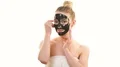 The happy woman with a black mask touching a face on the white background 4k or 4k+ Resolution