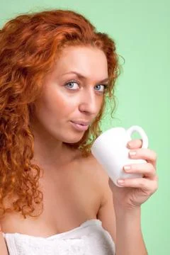 Happy woman with cup of tea or coffee wearing white towel Stock Photos