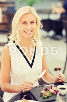 Happy woman eating dinner at restaurant terrace Stock Photos
