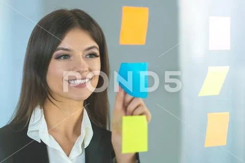The happy woman glues a sticker on the glass Stock Photos