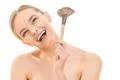 The happy woman holding a cosmetic brush on the white background Photo