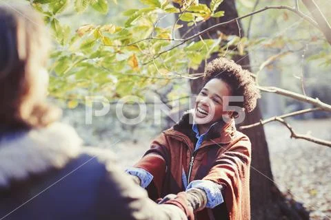 Happy woman holding hands with boyfriend in sunny autumn park Stock Photos