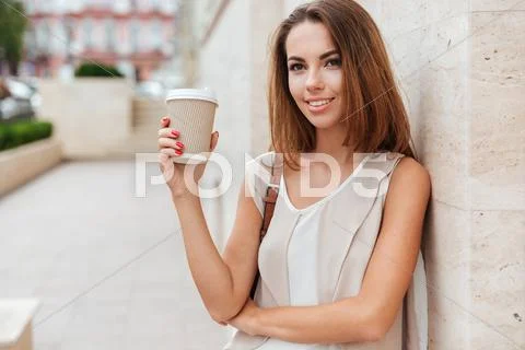 Happy woman holding take away coffee and looking at camera Stock Photos