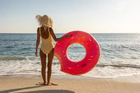 Happy woman with inflatable donut on a tropical beach. Stock Photos