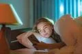 The happy woman lay on the bed and phone Photo