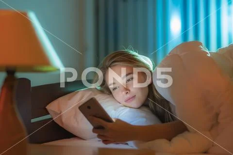 The happy woman lay on the bed and phone Stock Photos