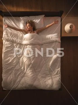 The happy woman lay on the bed and gesture. View from above Stock Photos