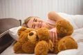 The happy woman lay on the bed with soft toy Photo